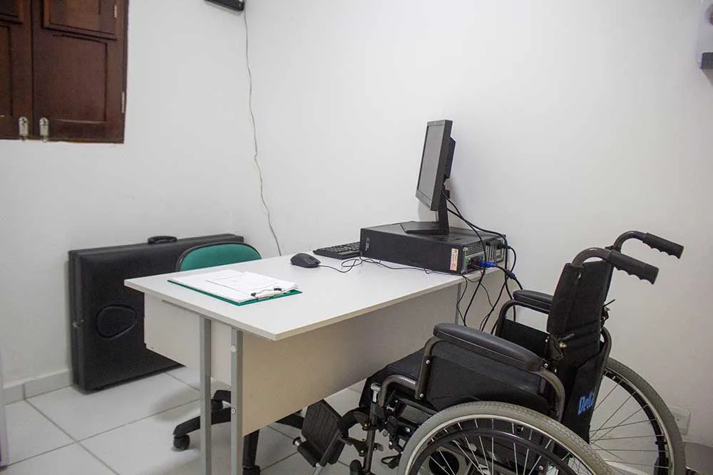 Consultório com escrivaninha, computador e cadeira de rodas