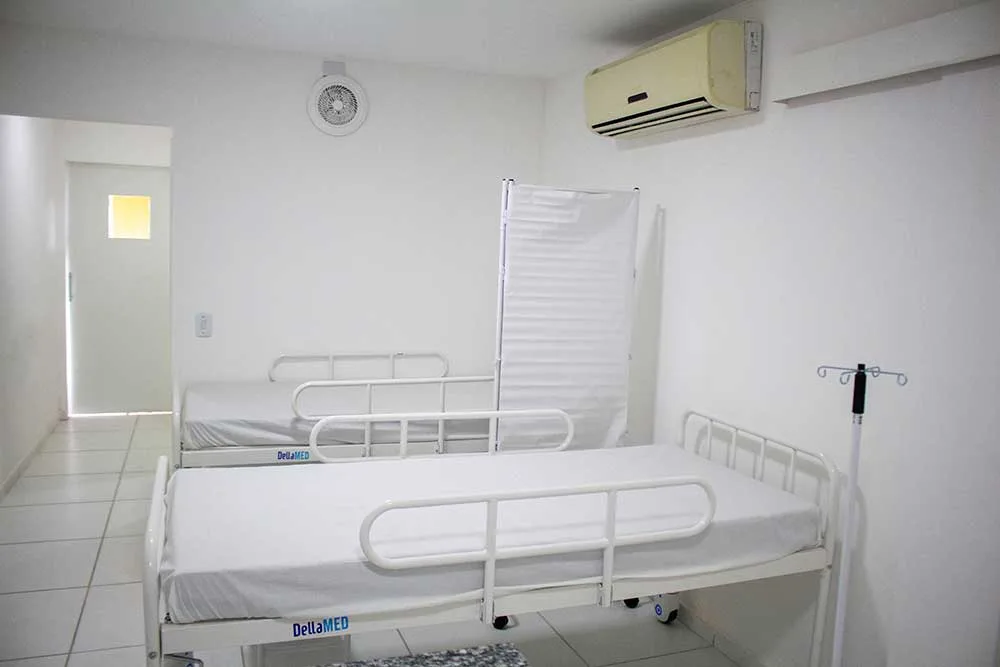 Leito hospitalar arrumado na enfermaria, com suporte de soro