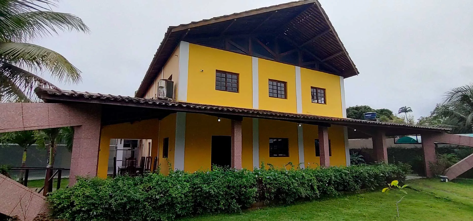 Fachada amarela da clínica vista em ângulo, com a varanda de baixo e a sacada de cima