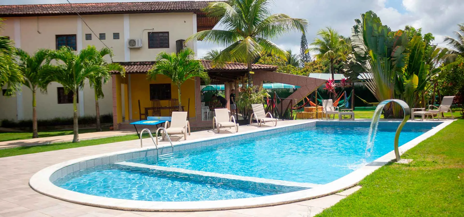 Fachada lateral da Reconciliar, com vegetação e o prédio amarelo ao fundo