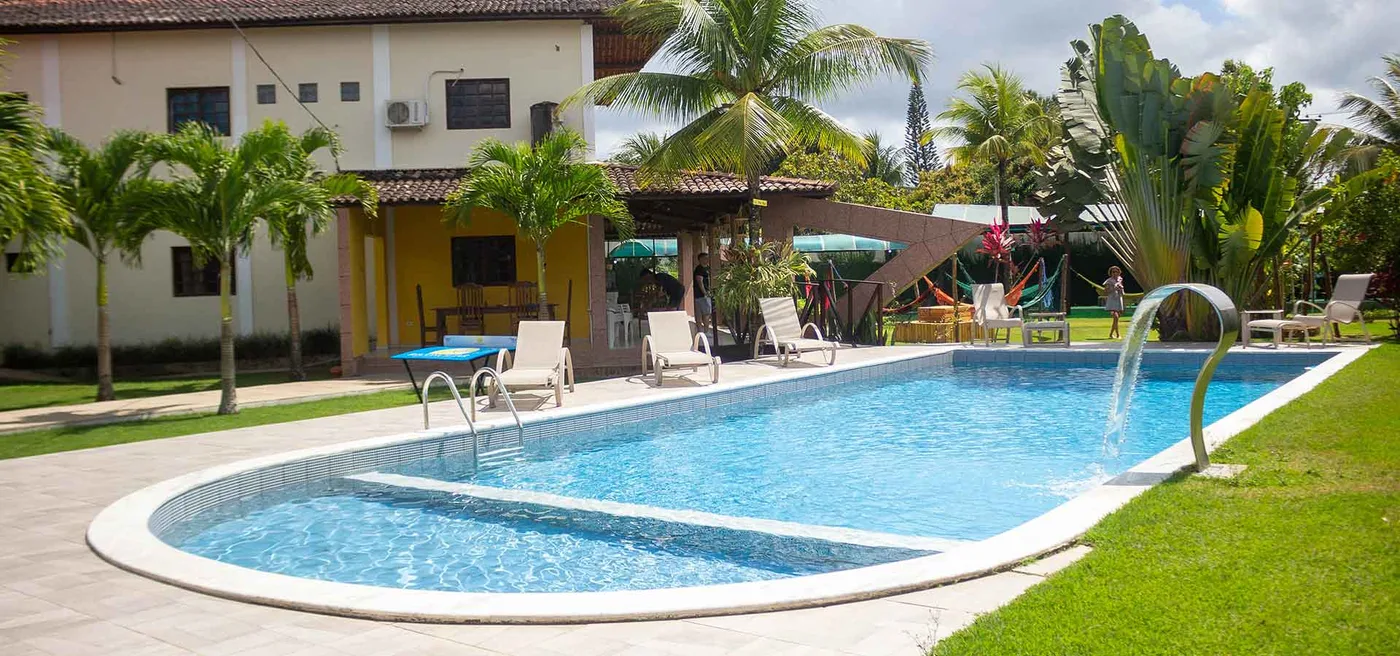 Área externa da clínica com piscina, espreguiçadeiras e vegetação tropical