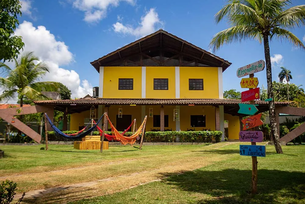 Prédio da clínica ao fundo, com as redes coloridas armadas no jardim e o painel de placas à direita